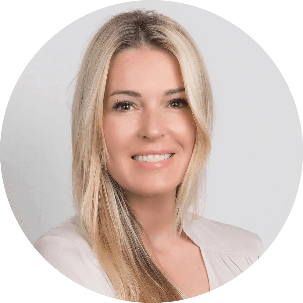 Portrait of a person with long, straight blonde hair, smiling effortlessly. They are wearing a light-colored top, exuding an aura of calm amidst Kommunikationskrisen, all set against a plain background that subtly highlights their poised confidence in Reputationsmanagement.