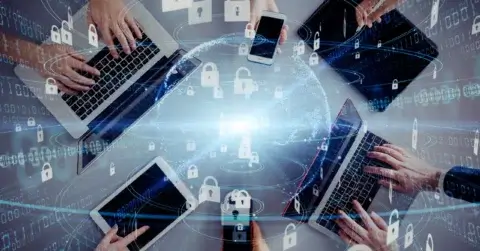 Several people use laptops, tablets, and smartphones at a table. Overlay graphics of locks and a globe symbolize digital security, data protection, and global connectivity. The composition conveys the theme of cybersecurity and technology integration.