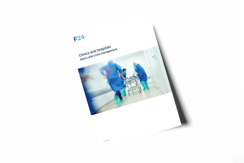 A booklet titled "Clinics and hospitals: Alarm and crisis management" with a blurred image of medical staff in blue scrubs quickly pushing a gurney down a hospital corridor.