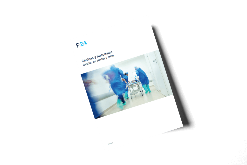 Cover of a document titled "Clínicas y hospitales: Gestión de alertas y crisis". It features a blurred image of medical staff in blue scrubs rushing a stretcher down a hospital corridor. The background is white with minimal text.