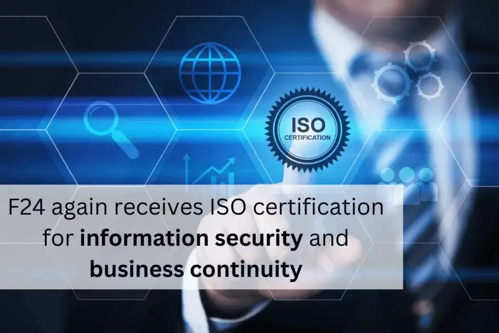 A person in a suit points to a digital ISO certification icon on a screen adorned with symbols like a globe and gears. Text overlay announces, "F24 achieves recertification for information security and business continuity.