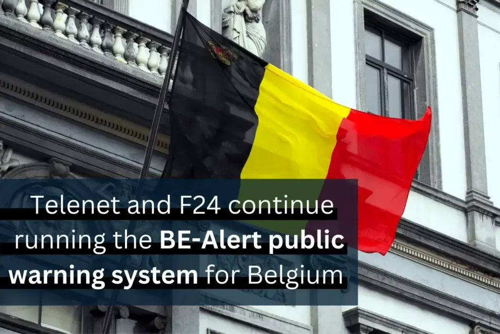 The image shows the Belgian flag flying from a building. Overlaid text reads: "Telenet and F24 continue running the BE-Alert public warning system for Belgium.