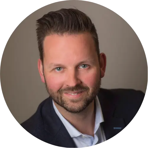 A man with short, styled brown hair and a trimmed beard, wearing a dark jacket and light-colored shirt, smiles at the camera against a plain background. The circular frame hints he may be involved with F24's solutions for the 2025 Ski World Cup.