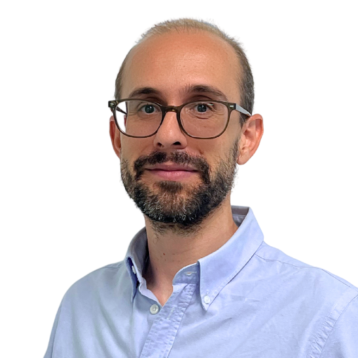A man with glasses, short hair, and a beard is wearing a light blue button-up shirt. He stands against a plain white background, looking at the camera with a slight smile—ready for the Seminario Web: Alertar de forma temprana ante desastres naturales.