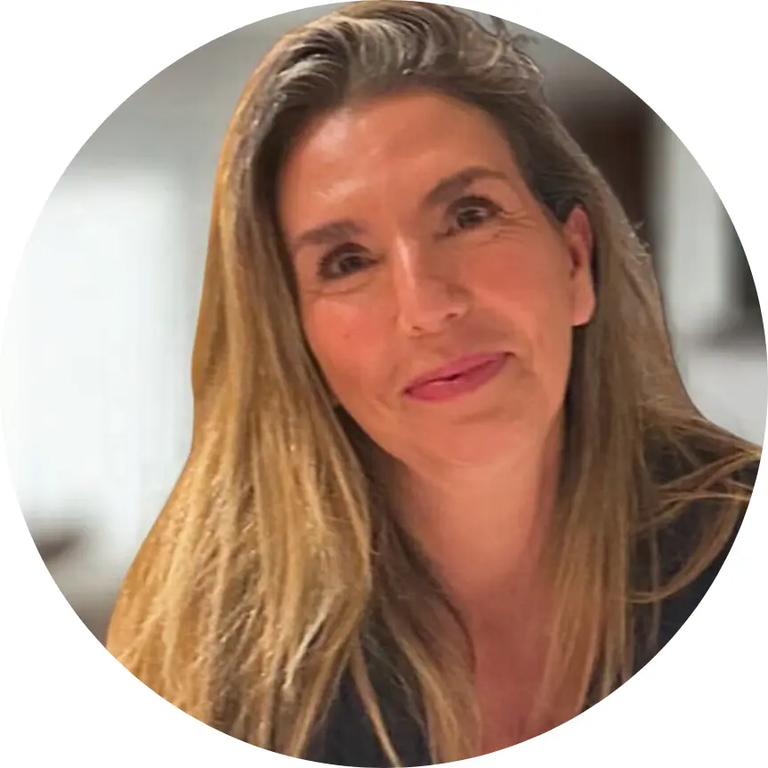 A woman with long, straight, blonde hair smiles gently at the camera. Indoors in a softly blurred setting, she wears a dark top. The circular frame gives a modern touch—perfect for sharing your Experience Tour Madrid moments.