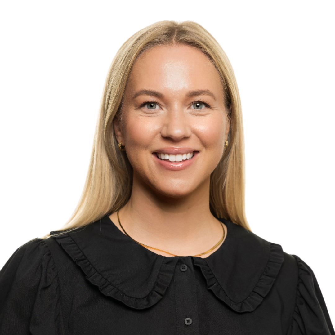 Portrait d'une femme souriante aux cheveux blonds et raides, portant un chemisier noir à col roulé et un collier en or, posé sur un fond blanc uni, évoquant l'élégante simplicité du style norvégien.