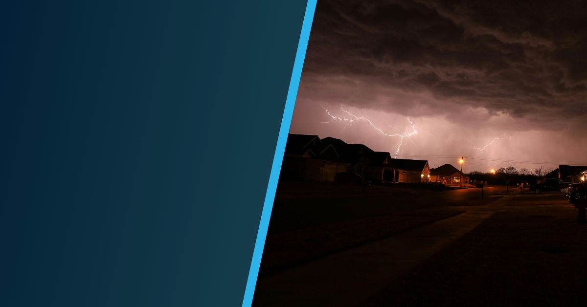 A dark, stormy night in a suburban neighborhood with dramatic clouds and flashes of lightning illuminating the sky above houses; the left side of the image is overlaid with a solid dark blue panel.