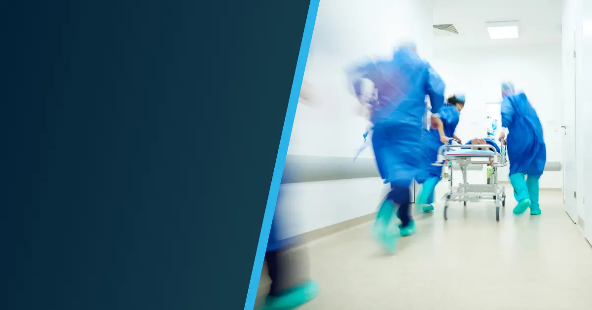 Several medical professionals in blue scrubs rush a patient on a stretcher down a hospital hallway, blurred to convey urgency. The scene highlights Krisenmanagement und Alarmierung im Klinikalltag – Einblicke aus dem Klinikum Oldenburg.