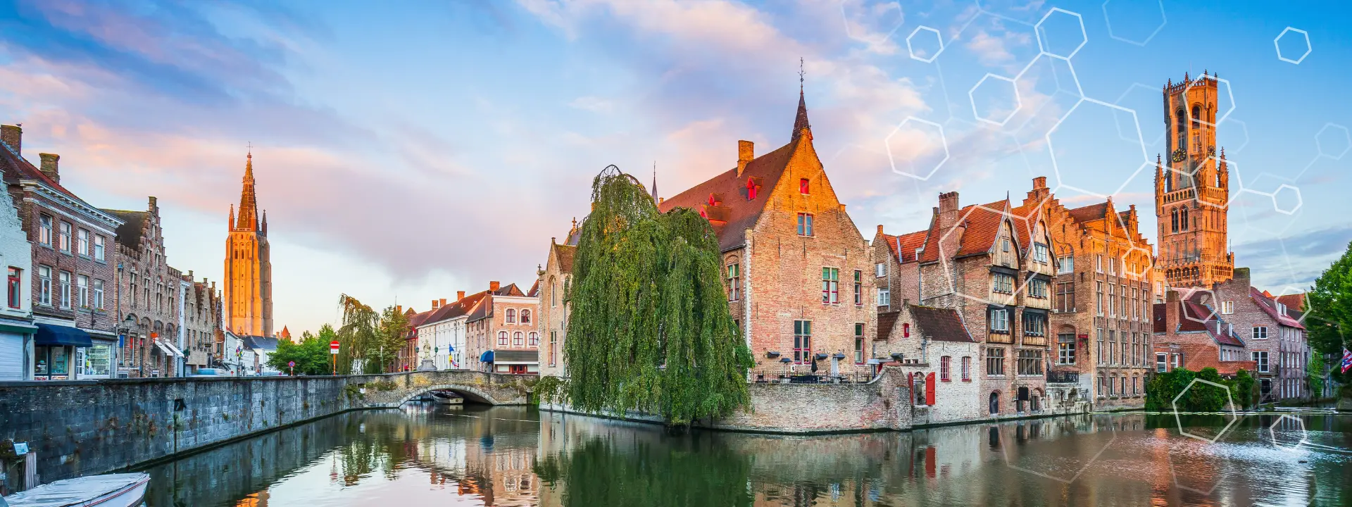 A scenic canal in Bruges, Belgium, reflects historic brick buildings and a tall church tower at sunset, with a partly cloudy sky and geometric shapes faintly overlaid on the right side.
